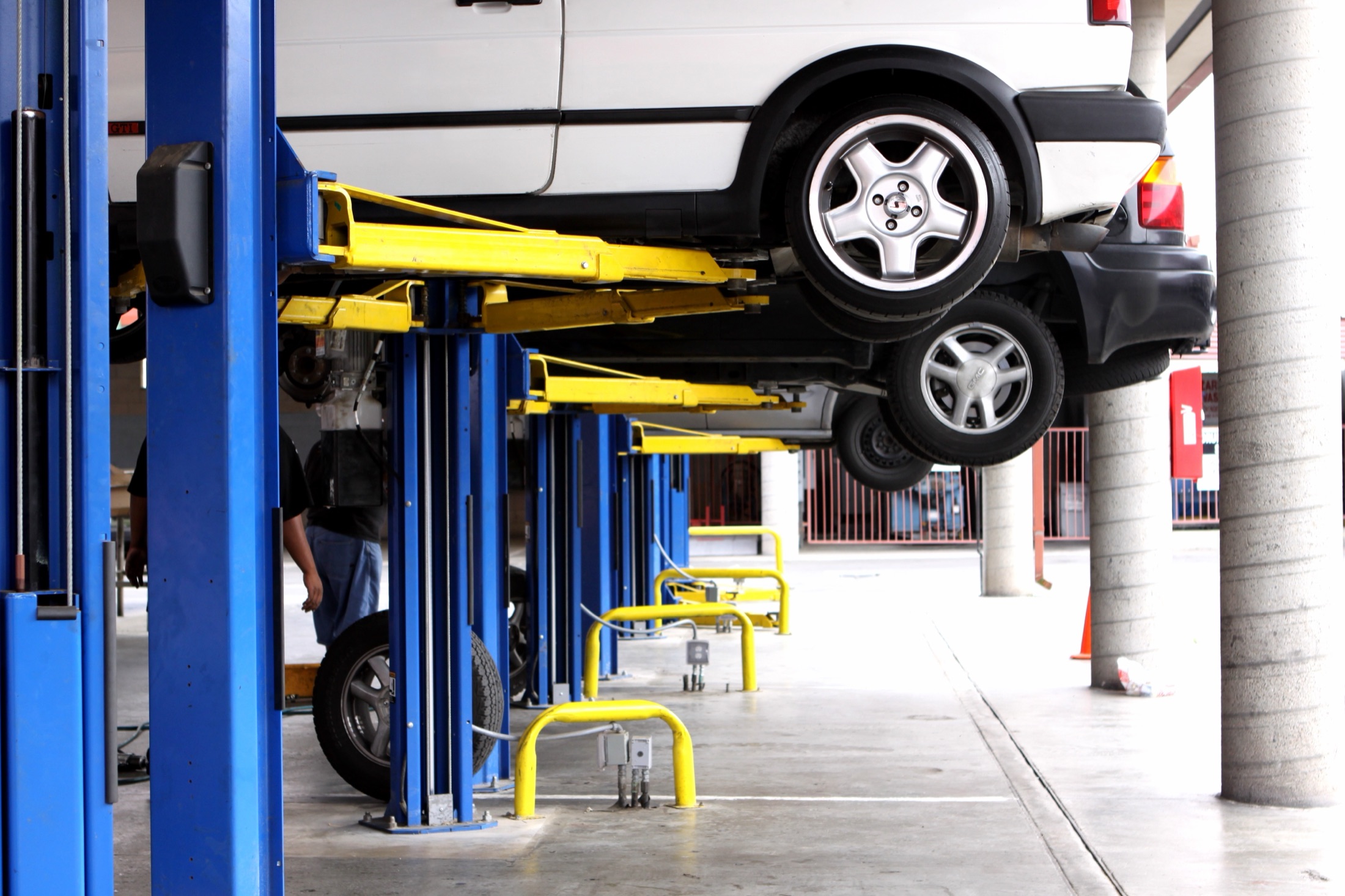 Vehicles positioned on workshop lifts inside an automotive service centre